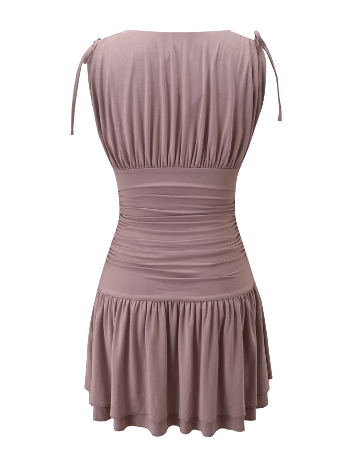 The HALONA MINI DRESS in mocha by TIGERMIST is shown from the back, featuring shoulder tie straps, a ruched waist, and a softly tiered gathered skirt for movement.