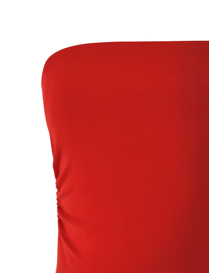 Close-up of a person wearing the HARRIETT RIB TUBE TOP - RED by TIGERMIST. This vibrant, strapless ribbed jersey top features ruched side details, and its slightly stretchy fabric creates a flattering bodycon silhouette that hugs the body snugly. The background is plain white.