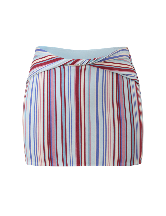 The TIGERMIST HAZE TWIST SKIRT – VARIEGATED STRIPE is a fitted, high-waisted mini skirt with an overlapping waistband and vertical blue, red, pink, and cream stripes on a light blue background.