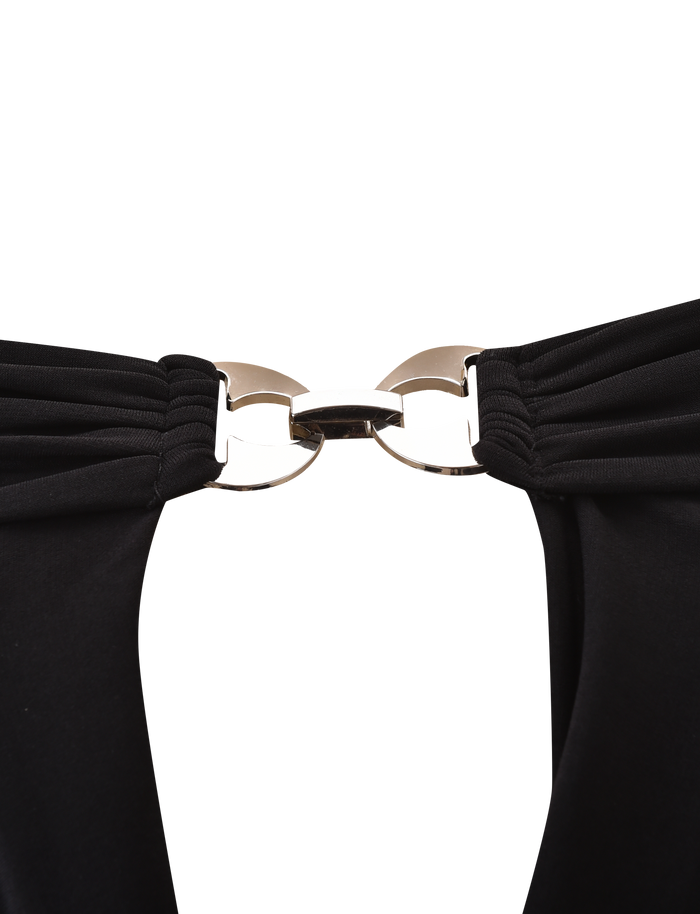 Close-up of a silver metal clasp joining two gathered black slinky jersey straps on the JENESIS LONG SLEEVE TOP by TIGERMIST, set against a plain white background.
