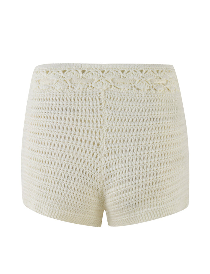 The JONAS SHORT - WHITE : CREAM from TIGERMIST is a pair of high-waisted crocheted shorts made from high stretch fabric. These cream-colored shorts showcase an intricate crochet pattern with a slightly scalloped design at the waistband and a simple, uniform pattern throughout the rest of the garment.