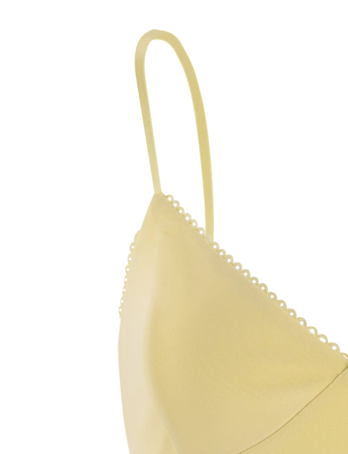 Close-up of the JULIANNA DRESS - YELLOW : LEMON from TIGERMIST, featuring a delicate scalloped trim. The image focuses on the shoulder strap and upper part of the garment, highlighting its soft fabric and minimalistic design. The white background makes the dress stand out.