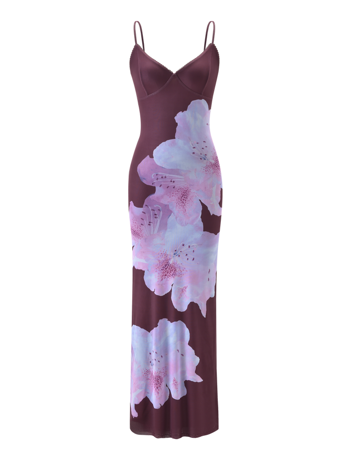 The JULIANNA MAXI DRESS - ZEN FLORAL by TIGERMIST features a sleeveless, fitted silhouette with adjustable spaghetti straps and bold light purple floral prints on the maroon front.