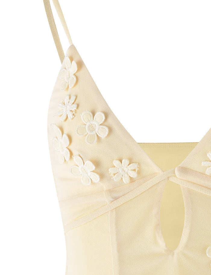 Close-up of a butter-yellow KATINA CAMI from TIGERMIST, showcasing its delicate embroidered floral patterns. The cami features thin shoulder straps, a V-neckline, and a small keyhole cutout in the center. The fabric appears to be sheer and lightweight.