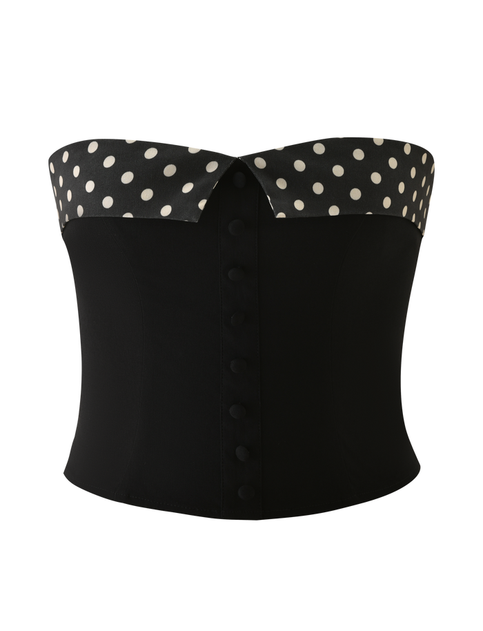 The KITTIE 2.0 BUSTIER by TIGERMIST is a black strapless corset in stretch suiting fabric, featuring a folded polka dot top edge and a front row of covered buttons.