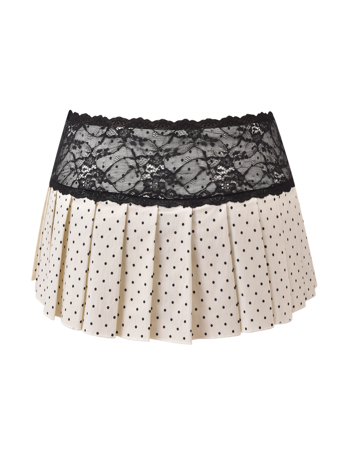 The KITTIE LACE SKORT - CREAM DOT by TIGERMIST features a cream pleated mini design with playful polka dots and a wide black lace waistband, crafted from stretch suiting fabric and shown against a plain white background.