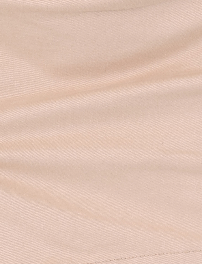 A close-up of smooth tan fabric with gentle folds, a subtle diagonal seam at the lower right, and the overlap waistband structure of the TIGERMIST KITTIE SKORT - TAN.