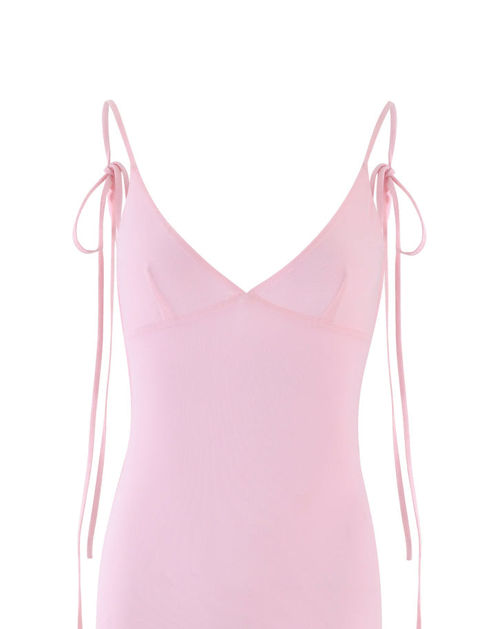 A Baby Pink sleeveless spaghetti strap dress with a deep V-neckline from TIGERMIST. The thin straps tie into bows at the shoulders. The form-fitting KYLAH DRESS - PINK is made of a semi-sheer fabric, set against a plain white background.