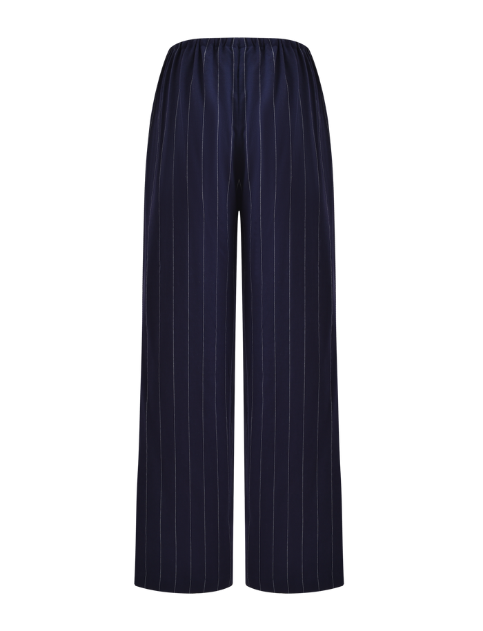 The LAINEY PANT - NAVY PINSTRIPE by TIGERMIST features navy blue wide-leg linen with vertical white pinstripes and an elasticated waist, shown against a plain white background.