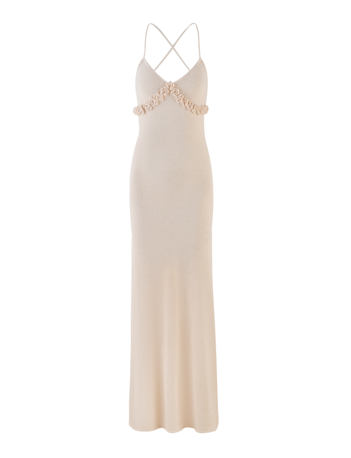 The TIGERMIST LAVELLE MAXI DRESS in cream features a fitted bodice with floral appliqués, adjustable criss-cross straps, an open back, and a slightly flared skirt.