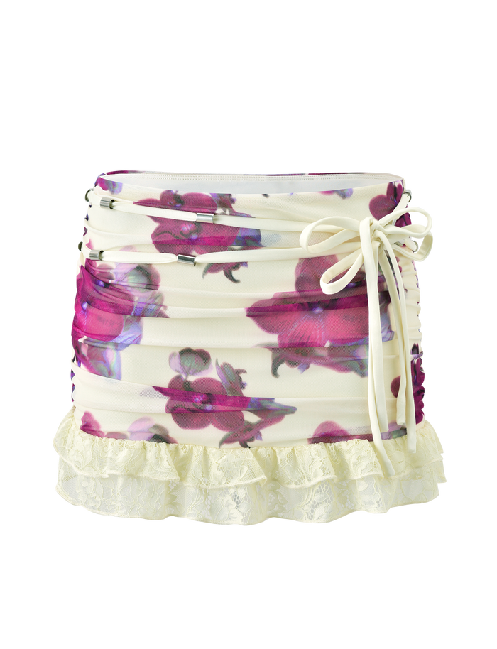The TIGERMIST LILIAH MINI SKIRT - ORCHID HAZE features a cream floral mesh with pink orchid print, ruched sides, side tie detail, and a ruffled lace hem.