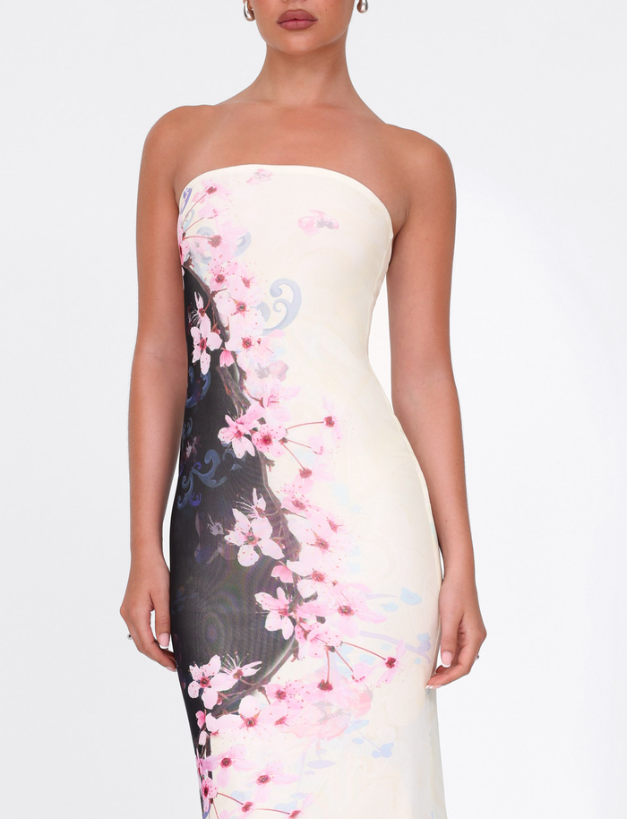 A woman models the TIGERMIST LILLIAN MAXI DRESS in cherry blossom floral print, featuring a strapless mesh design in pink and white tones, standing against a plain white background with her hair up.