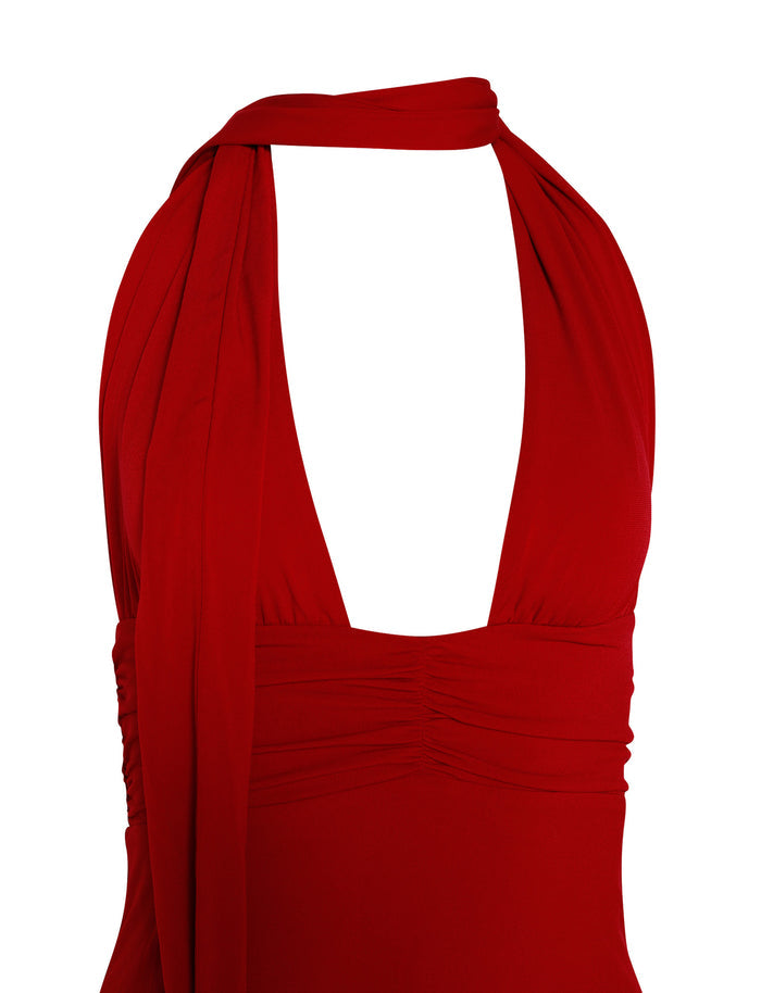 A close-up image of the TIGERMIST LUNA DRESS - RED : FIRE ENGINE RED. This sleeveless halter neck dress showcases a deep V-neckline and ruched detailing at the bust, with a long tie draped around the neck. The fabric exhibits a smooth texture.