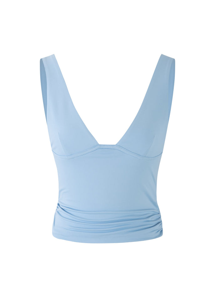 The LUNARIA TOP - BLUE : BABY BLUE from TIGERMIST is a light blue sleeveless crop top featuring a deep V-neckline. It has slightly ruched fabric on one side, creating a fitted silhouette, and the material appears to be smooth and stretchy. The top is showcased against a plain white background.