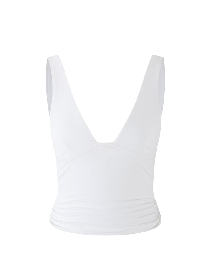 The LUNARIA TOP from TIGERMIST is a white, sleeveless V-neck top featuring a fitted silhouette. The smooth and slightly stretchy fabric offers a streamlined and elegant look. It also features wide shoulder straps and gathered detailing on the sides near the waist.