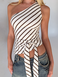 A woman wears the TIGERMIST LYLE ONE SHOULDER TOP in yellow stripe, featuring a front waistband tie, paired with faded blue jeans. Only her torso is shown against a plain background.