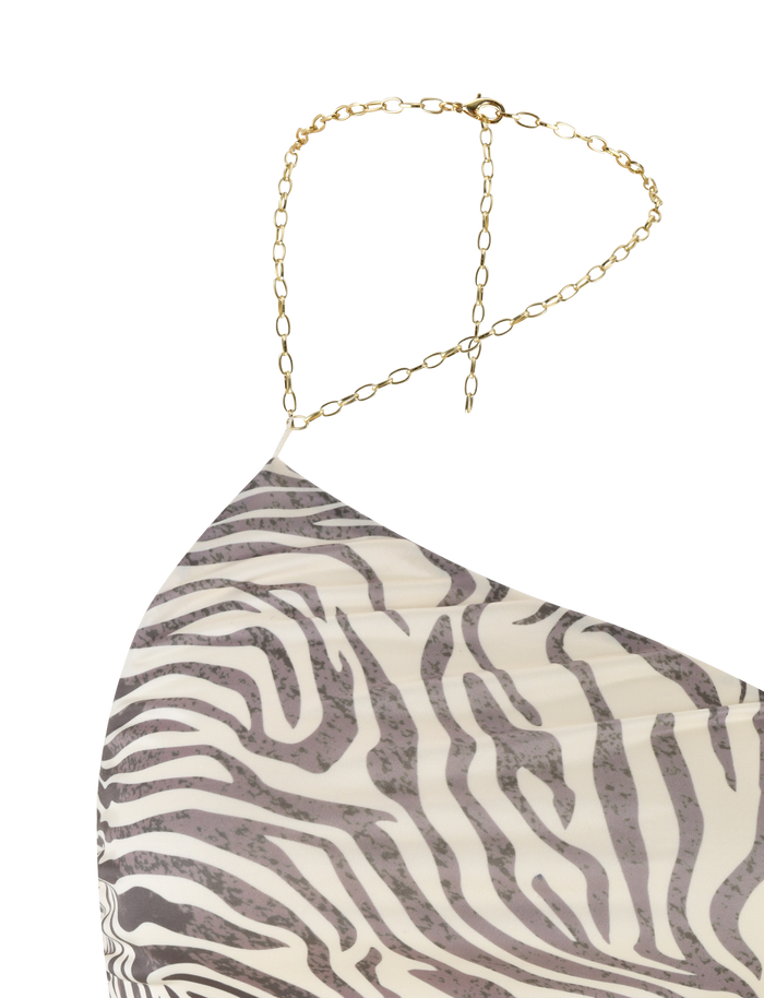 A close-up of the TIGERMIST LYRA TOP - NEUTRAL : ZEBRA, a cropped zebra-print top featuring a thin gold chain strap draped over the shoulder.