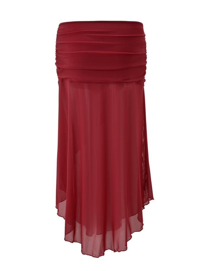 The TIGERMIST MARIANA SKIRT - RED is a knee-length, asymmetric wrap skirt in burgundy chiffon with a ruched waistband and sheer overlay, offering a soft drape and timeless, layered style.
