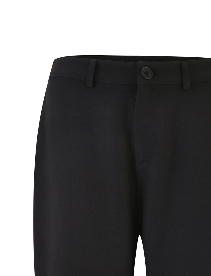 The image showcases a close-up view of the waist and upper part of the MARJORIE PANT - BLACK by TIGERMIST. These trousers feature a single button and zipper closure, complemented by belt loops at the waistband. The fabric looks smooth, embodying a simple and classic design.