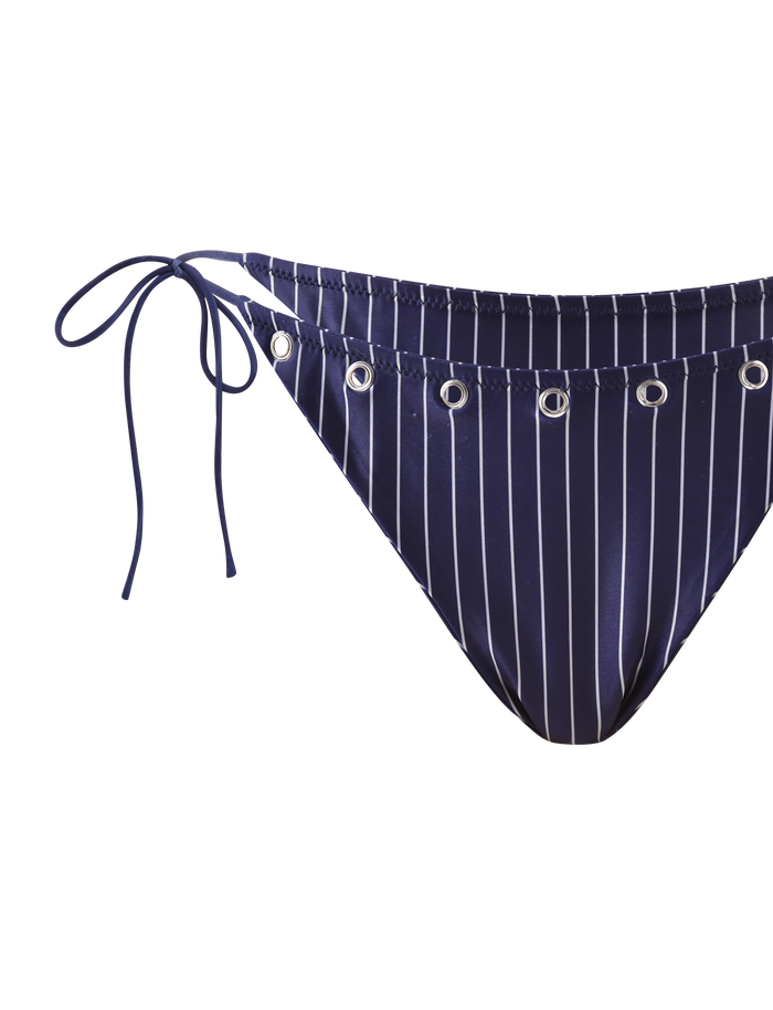 The MARREN BIKINI BOTTOM - NAVY PINSTRIPE by TIGERMIST features silver eyelets on the waistband and adjustable side ties on the left hip for a chic, customizable fit.