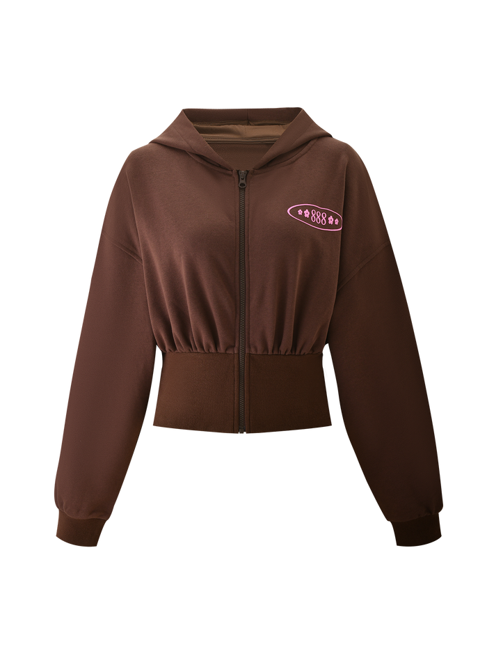 The MERRYN HOODIE - CHOCOLATE by TIGERMIST is a cropped brown zip-up with long sleeves, ribbed hem and cuffs, a hood, and a small pink "888" star puff print on the left chest.