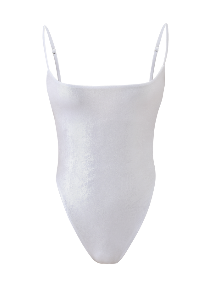 The MINERVA BODYSUIT - PEARL by TIGERMIST is a backless white velvet bodysuit with thin adjustable spaghetti straps, a straight neckline, and high-cut legs, shown on a plain white background.