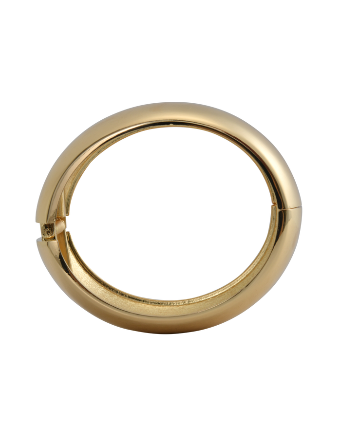 The MIRAH CHUNKY BANGLE - GOLD by TIGERMIST shines in gold with a smooth finish and bold design—ideal for pairing with your favorite gold hoop earrings for a striking, coordinated style against any backdrop.
