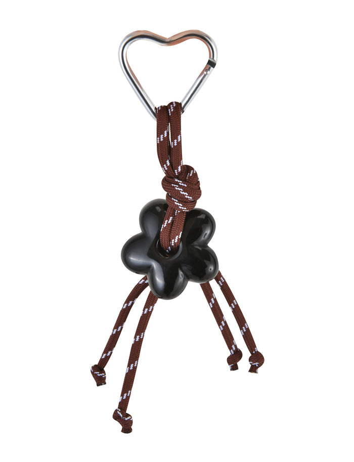 The TIGERMIST MIRIAM KEYCHAIN - CHOCOLATE features a heart-shaped metal clip attached to a brown rope with a black flower charm, its four ends whimsically tied off for an elegant touch.