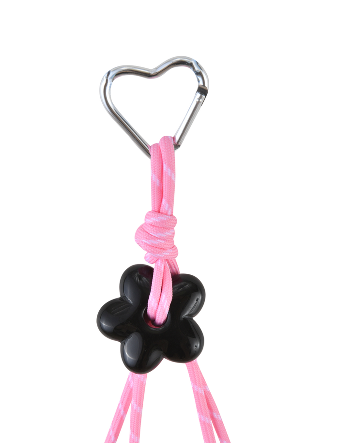 The MIRIAM KEYCHAIN - HOT PINK by TIGERMIST features a heart-shaped clasp and a pink cord threaded through a black flower charm, adding a unique accent.