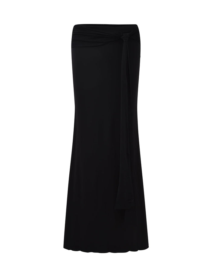 The MIST SKIRT - BLACK by TIGERMIST is a long, slim-fit skirt that boasts a high waistband and a knot detail with a hanging tie at the waist, creating a subtle draped effect. It features a slight flare at the bottom and has a smooth texture, embodying TIGERMIST's signature style.