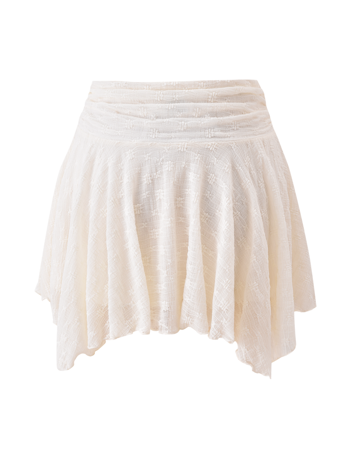 The TIGERMIST MYLAH MINI SKIRT in ivory features eyelet lace, a ruched waistband, and an asymmetrical handkerchief hem, shown on a plain background.