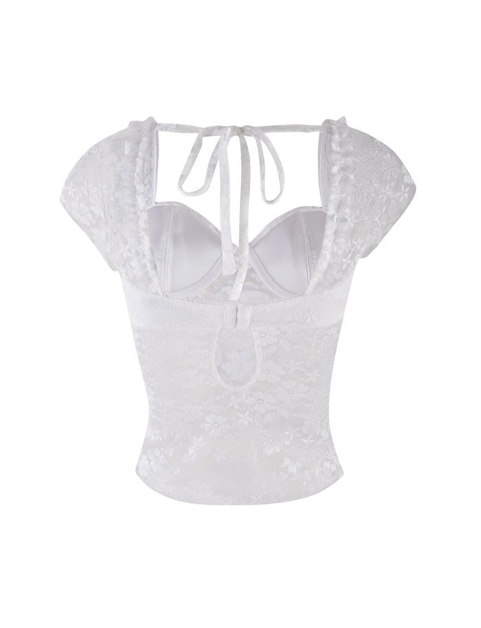 The NYRA TOP - WHITE by TIGERMIST is a white lace bustier top with short sleeves, sheer shoulder straps, an open back with upper tie, floral lace pattern, and a lower back cutout.