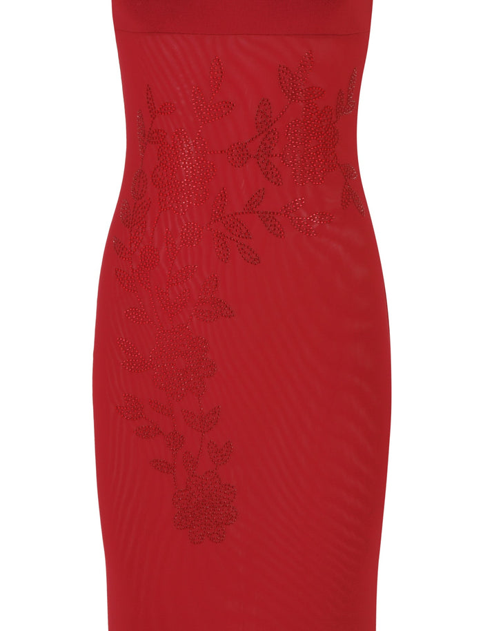 A close-up of the OCTAVIA MAXI DRESS - RED : CHERRY RED by TIGERMIST reveals its intricate floral embellishments. The textured design appears embroidered, adding depth and detail to the fabric. This maxi-length dress features a form-fitting silhouette that exudes elegance.