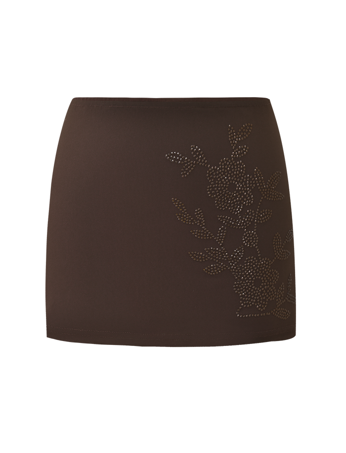 The TIGERMIST OCTAVIA MINI SKIRT - CHOCOLATE SPARKLE is a brown mini skirt with subtle floral embellishments made of small, shiny studs on one side, displayed against a plain white background.