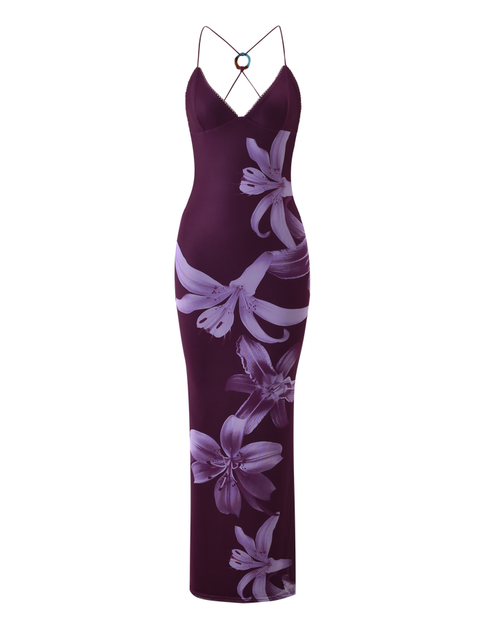 The TIGERMIST ORIELLE MAXI DRESS - PLUM ORCHID is a sleeveless, fitted floor-length dress with thin spaghetti straps, featuring a bold floral print of large lilies in purple hues across the fabric.