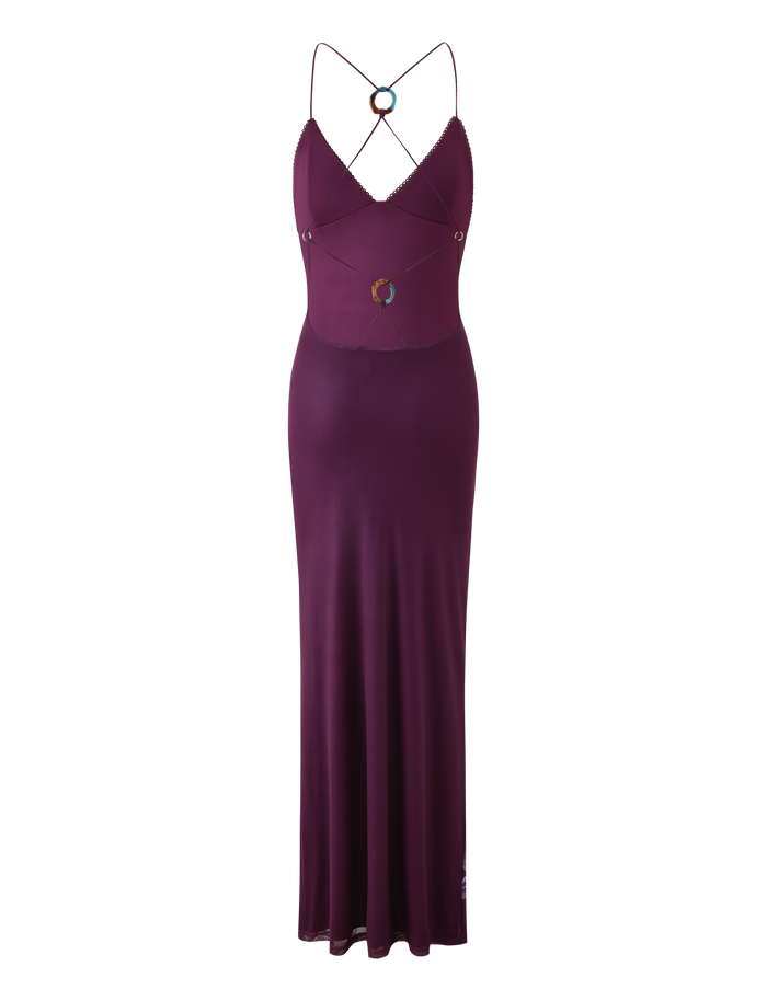 The TIGERMIST ORIELLE MAXI DRESS in Plum Orchid is a sleeveless, floor-length dress with thin crisscross spaghetti straps, circular ring accents at the chest and waist, and a strappy back.