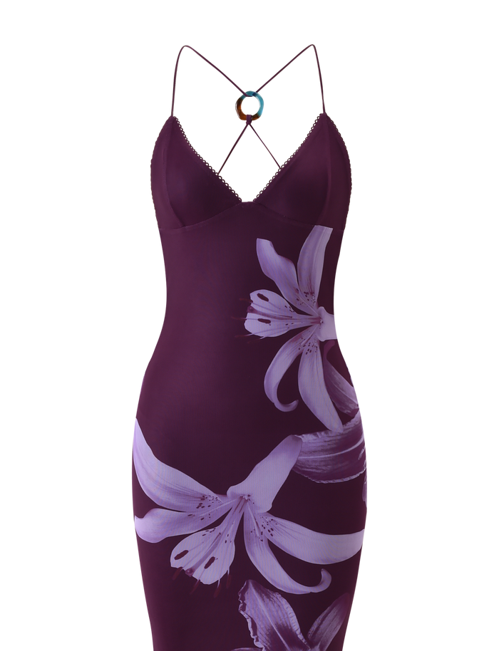 The TIGERMIST ORIELLE MAXI DRESS - PLUM ORCHID features a fitted design, bold light purple floral print on the front, thin crisscross straps, and a circular metal accent highlighting the strappy back.