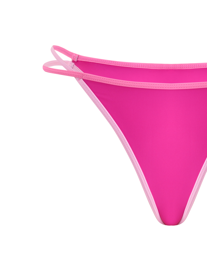 Close-up of the TIGERMIST PALMER BIKINI BOTTOM - BERRY, featuring bright pink fabric, light pink trim, sporty number 22 print, and double side straps, displayed against a white background.