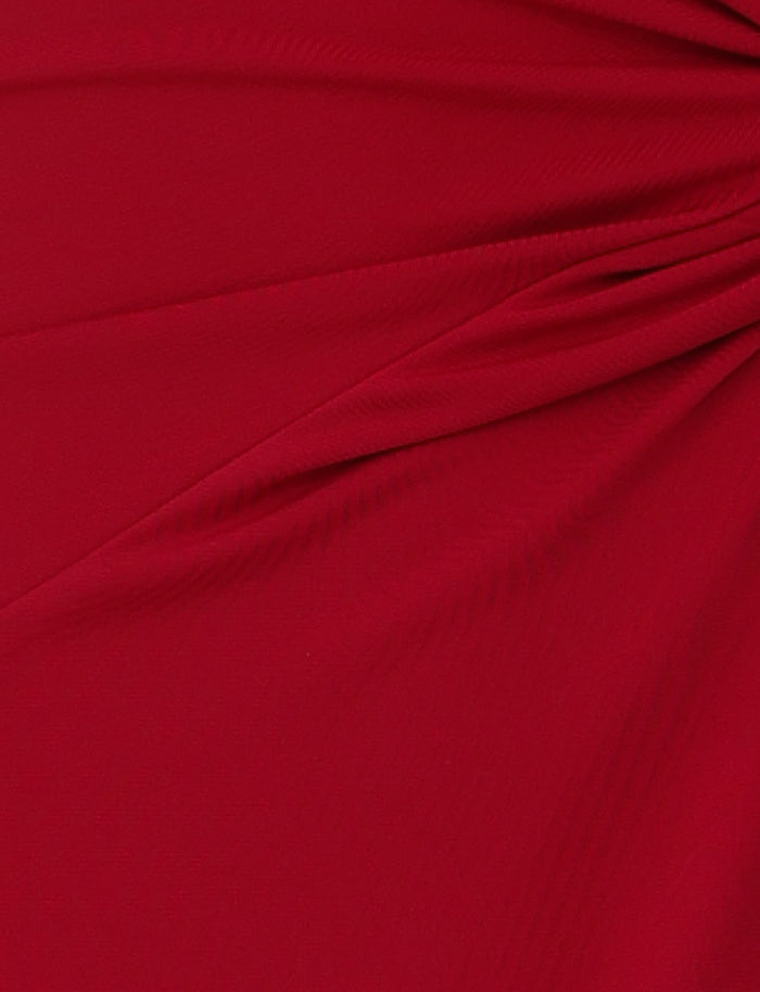 Close-up of the PARRIS DRESS - RED by TIGERMIST, showcasing its rich, vibrant color with subtle draping and folds reminiscent of a red halter neck dress. The fabric appears to be gathered slightly, creating a series of soft pleats and a textured surface.