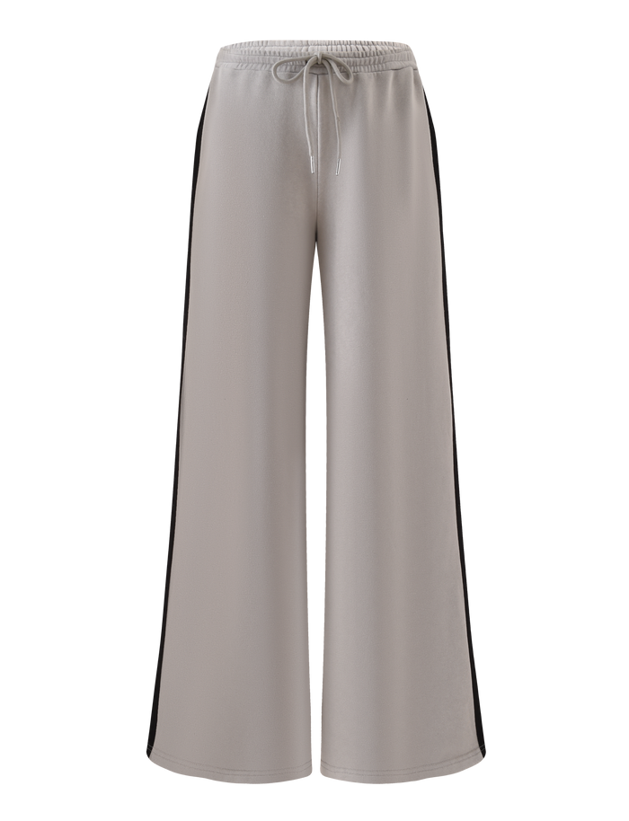 The PAYTON TRACKPANT - STONE by TIGERMIST features light gray cotton, an elastic waistband with drawstring, and black side stripes for a modern sporty look. Shown here against a plain white background.
