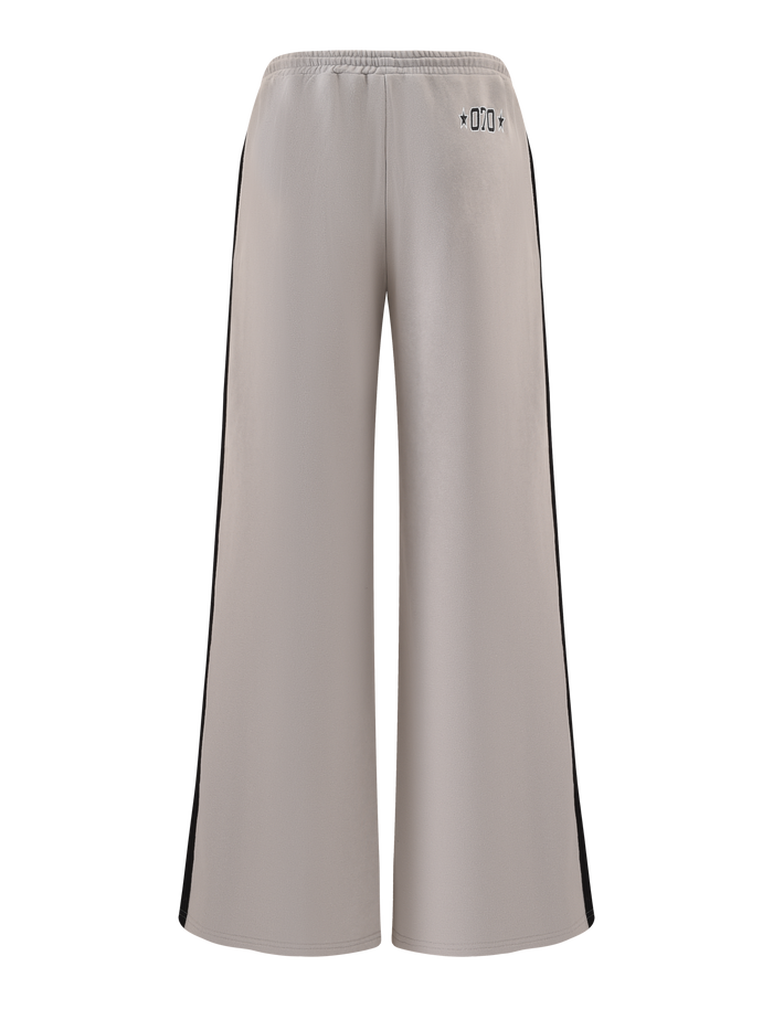 The PAYTON TRACKPANT - STONE by TIGERMIST features a sporty grey design with wide legs, black side panels, an elastic waistband, and subtle black symbols at the back waist, shown against a white background.