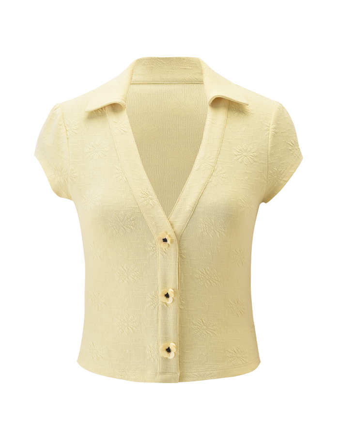 The QUINLAN TOP - LEMON by TIGERMIST features short sleeves, a collar, deep V-neck, and four front buttons. Made from stretchy fabric with a subtle floral texture for added charm.