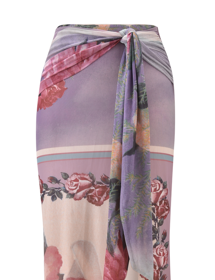 The RAFFIE MAXI SKIRT - POSTCARD FLORAL by TIGERMIST is a high-waisted maxi skirt with a knot front, gathered waist tie, and rose print in purple, pink, and beige.
