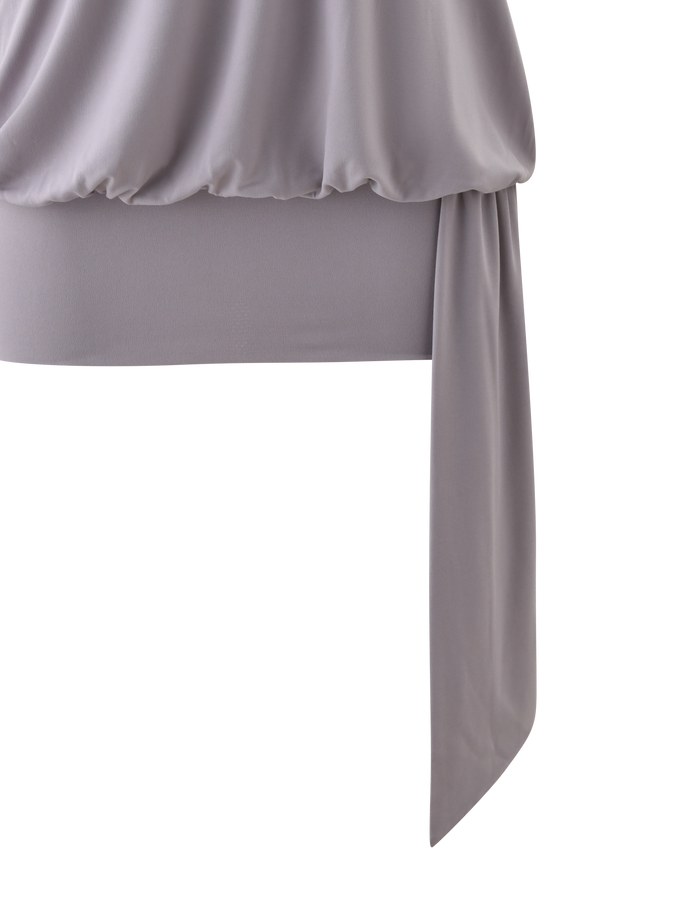 A close-up of the TIGERMIST RAVENNA MINI DRESS in Cool Slate, featuring gathered, draped fabric with silver eyelet trim and a long, loose sash, set against a white background.