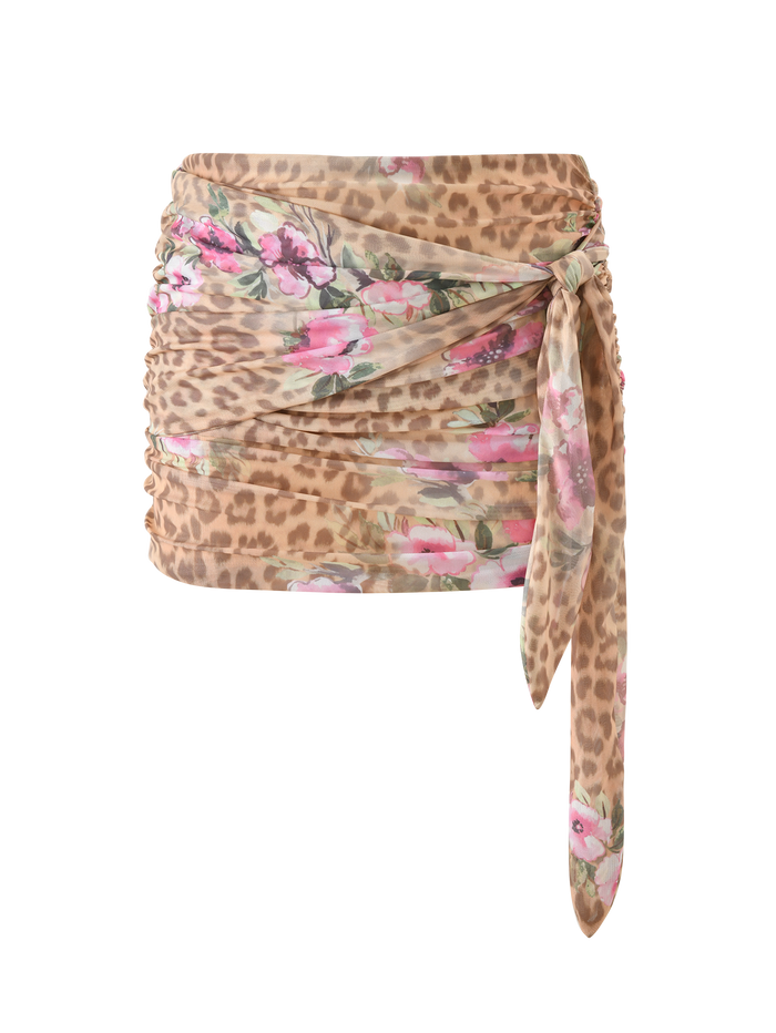 The RISA MINI SKIRT - LEOPARD FLORAL by TIGERMIST features beige and pink leopard floral prints, gathered and ruched sides, and a long sash tie draped at the front right.