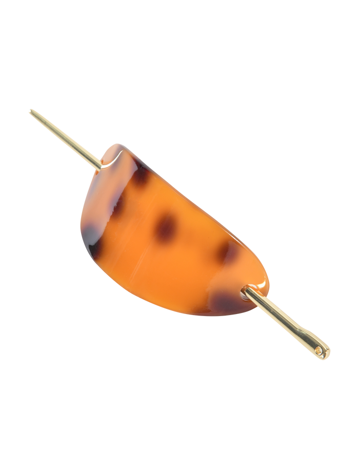 The RUKA BARRETTE - TORTOISESHELL by TIGERMIST features a gold bar closure threading through its curved, acrylic design in rich brown and amber tones, shown against a white background.