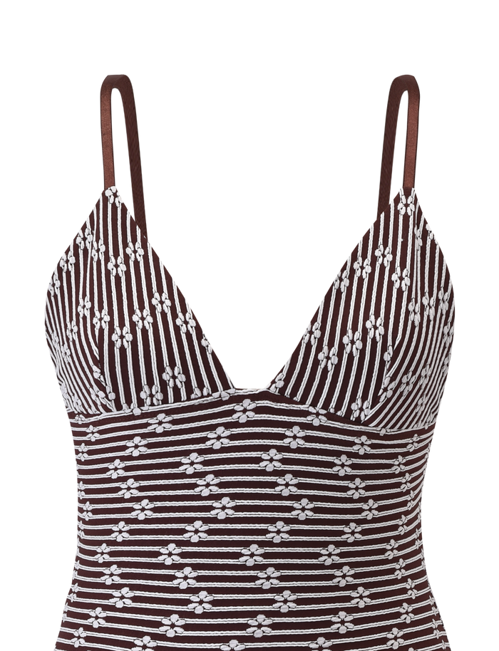 The SAHRA MINI DRESS by TIGERMIST features chocolate brown stripes, a textured floral and geometric pattern, thin shoulder straps, a V-neckline, and a small triangular cutout at the center.
