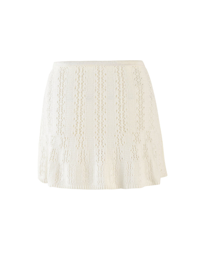 The SANDOR SKIRT - WHITE by TIGERMIST is a white, knee-length crochet skirt with a flared design. It features intricate vertical patterns with both solid and open stitch sections, creating a textured and airy look. The elastic waistband provides a snug fit.