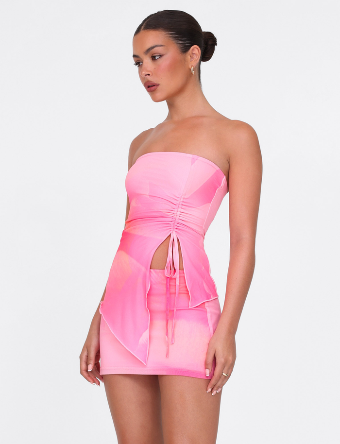 A woman wears the TIGERMIST SARIAH TOP in Macro Floral Pink Blossom, a strapless, ruched top with bodycon fit and side cutout, styled against a plain white background.