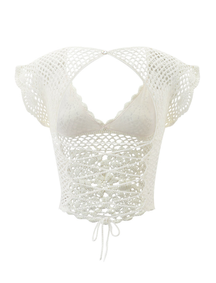 The SASHA CROCHET TOP - IVORY by TIGERMIST is a white crochet lace crop top with corset-style details, scalloped cap sleeves, an open chest cutout, and a waist tie.